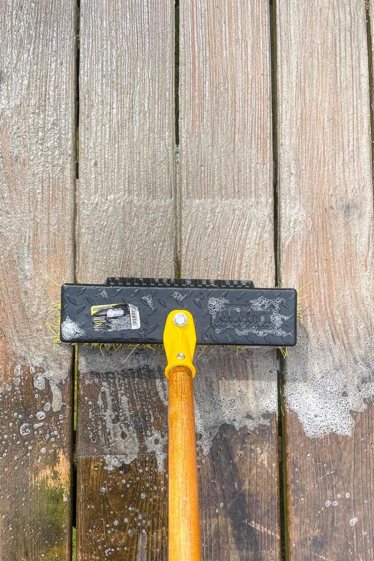 cleaning the surface of a deck with deck cleaner and a scrub brush