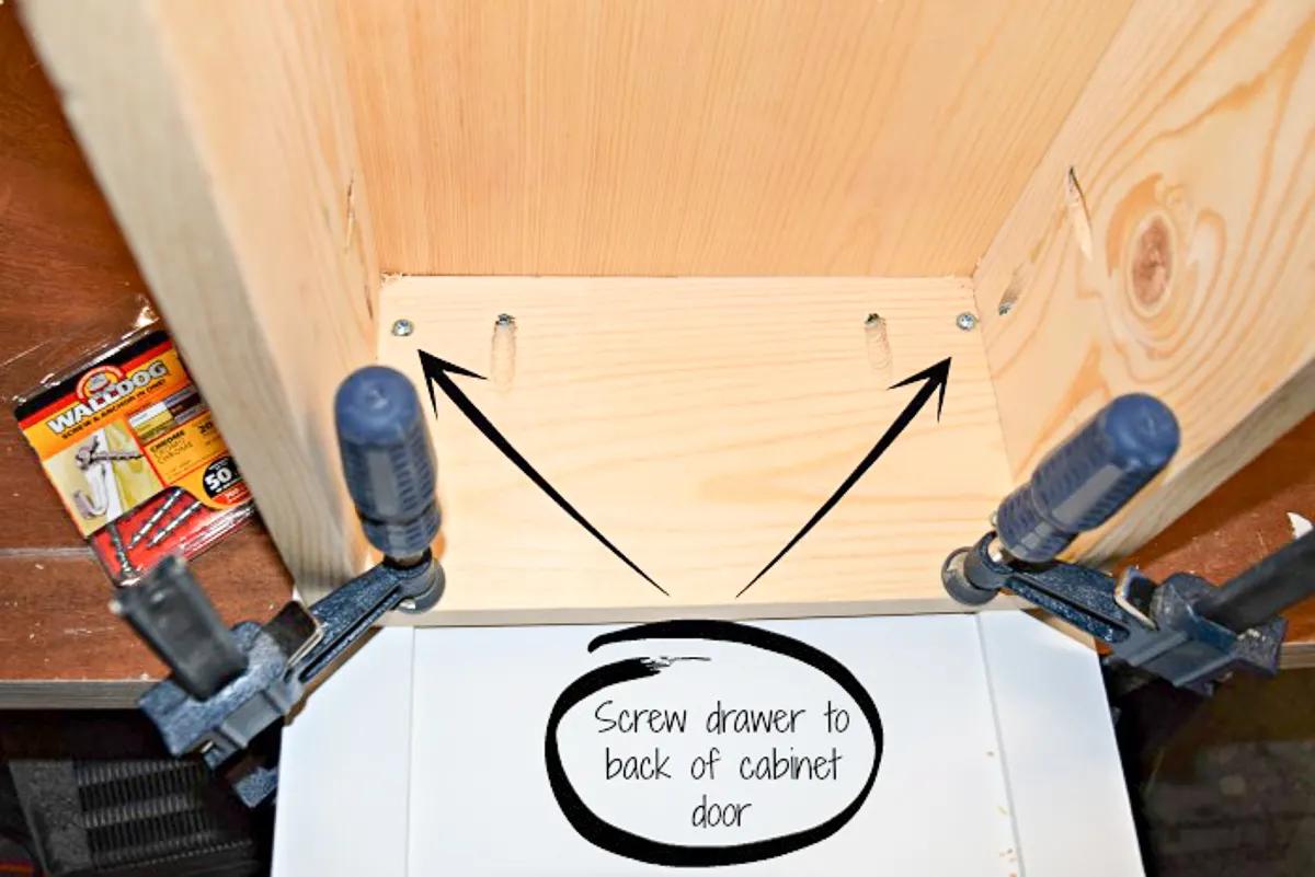 attach the cabinet door to the trash can cabinet drawer with screws
