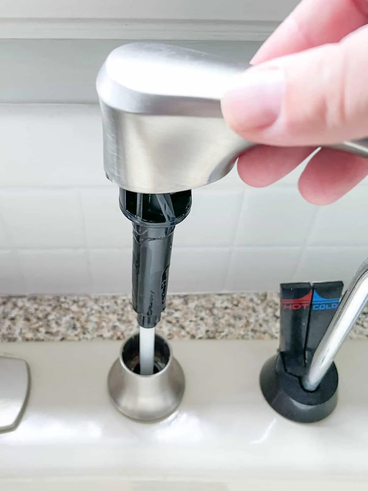 inserting pump tube into kitchen sink soap dispenser