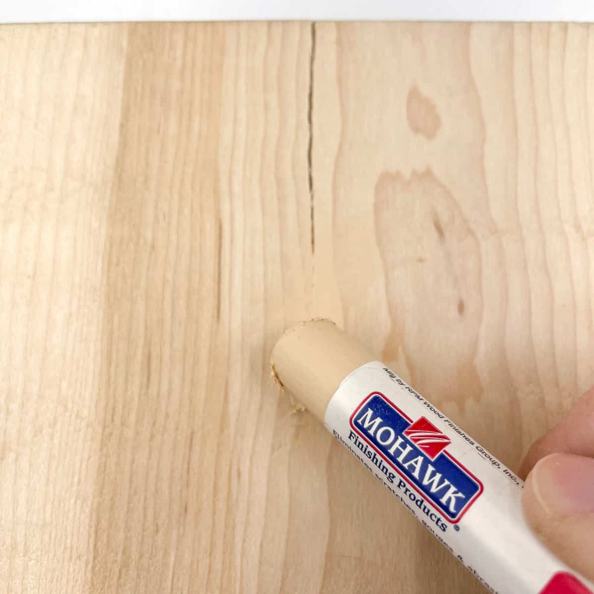 repairing a crack in wood with wood putty stick
