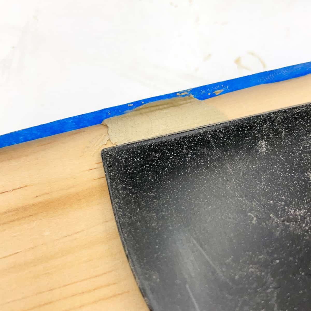 creating a wood filler dam with painter's tape to repair dented corner of wood board
