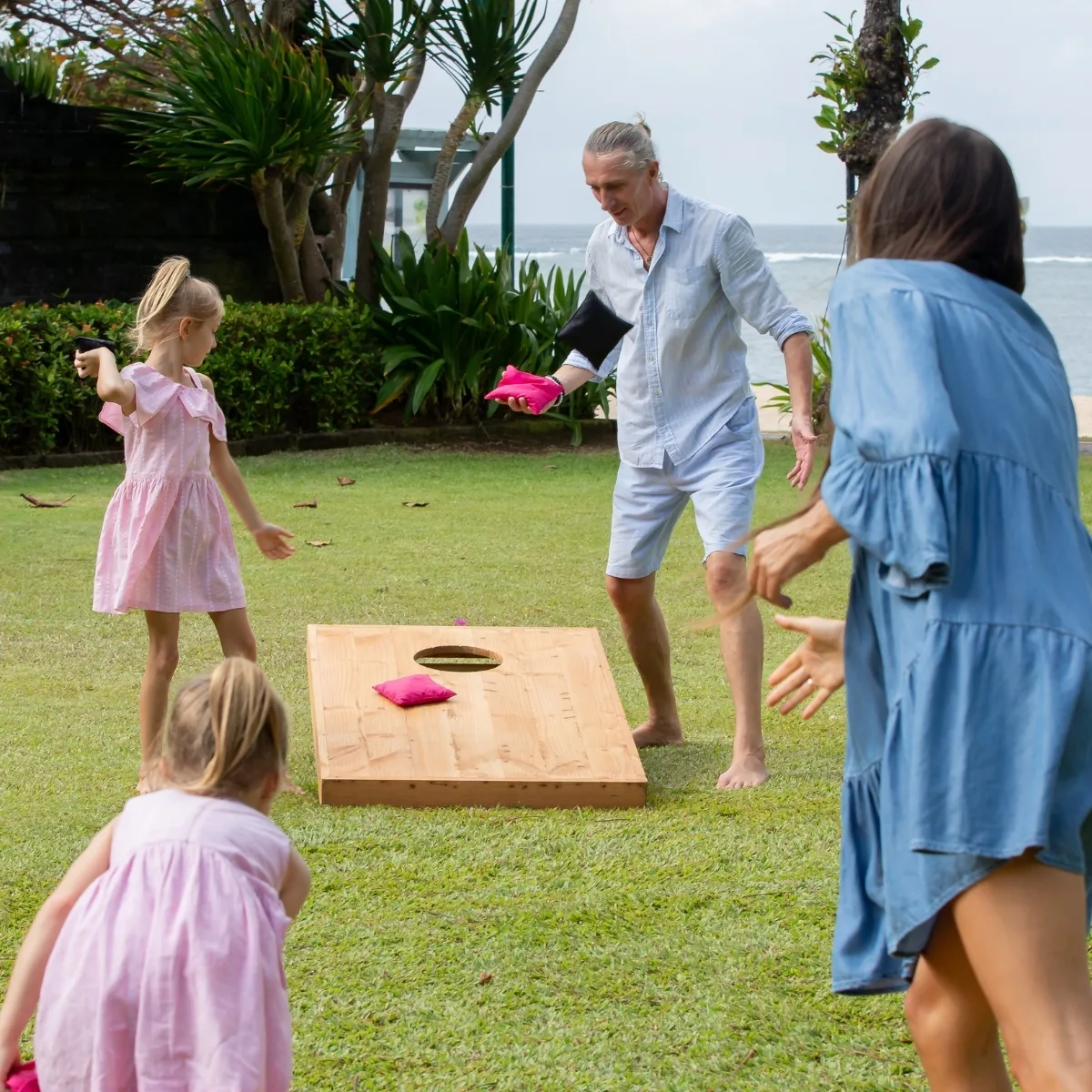 family playing cornhole at the beach