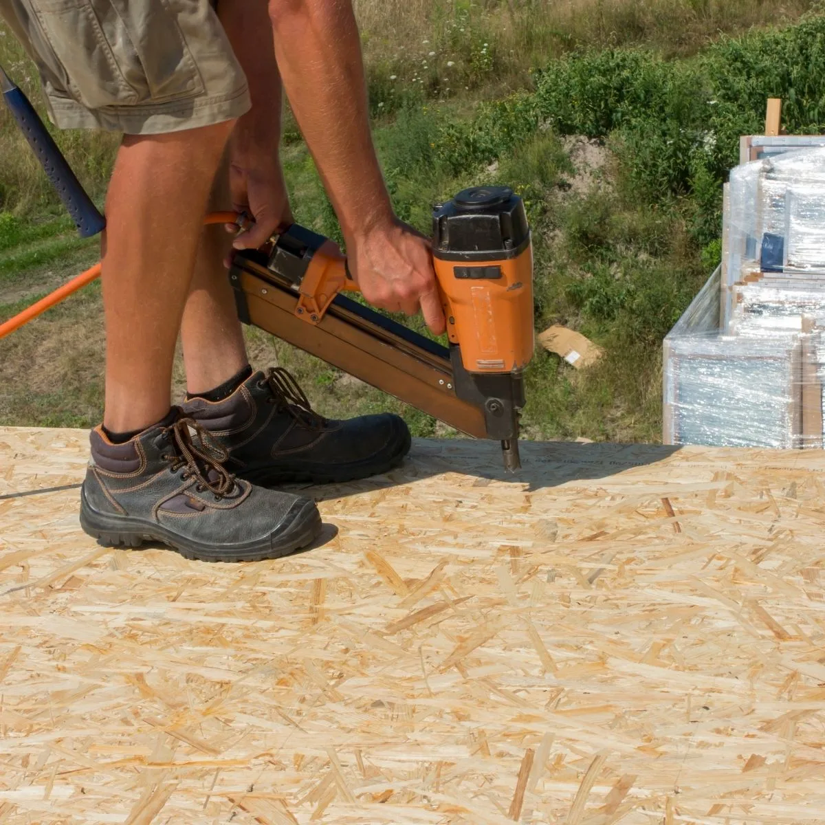 construction worker nailing OSB sheet to flooring joists