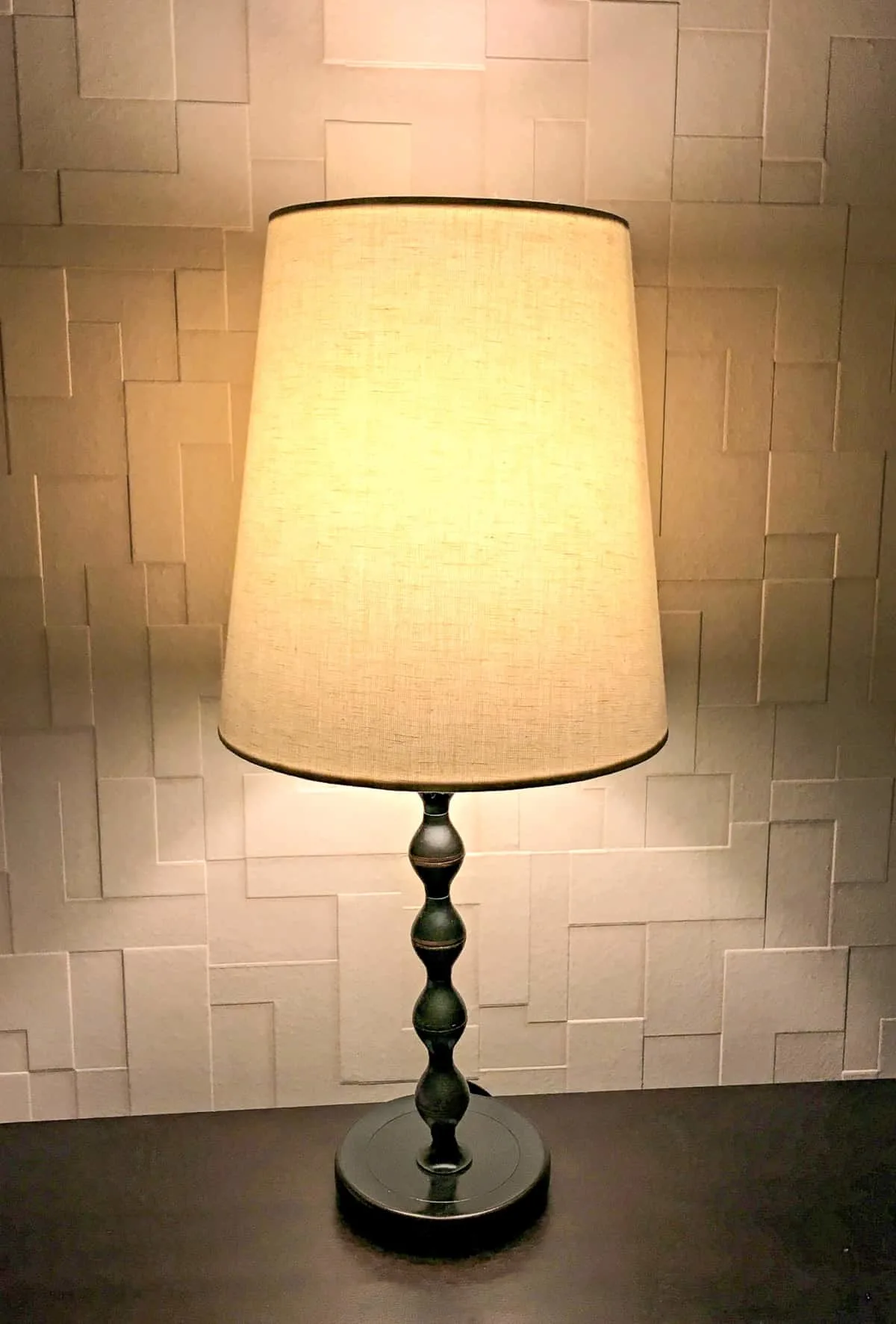 bedside lamp in front of textured wallpaper accent wall