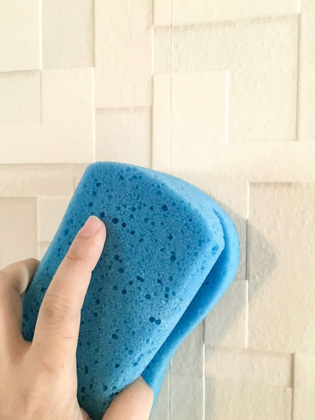 wiping off excess wallpaper paste with a sponge