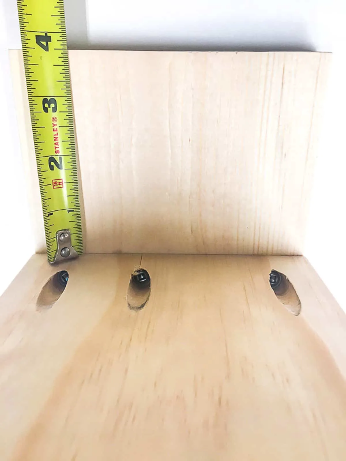 checking the height of the second desk shelf with a tape measure