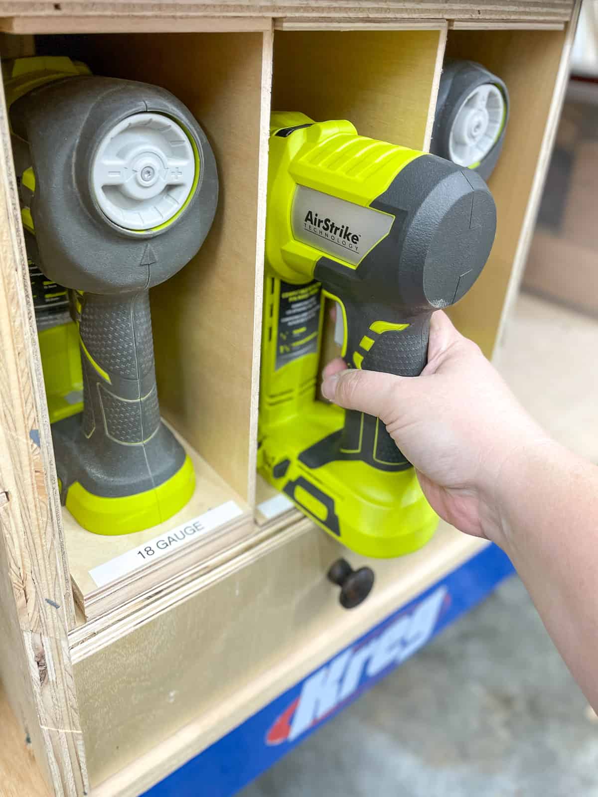 pulling a pin nailer out of the nail gun storage box