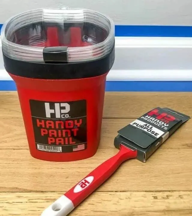 image of red paint pail and paint brush in front of baseboard