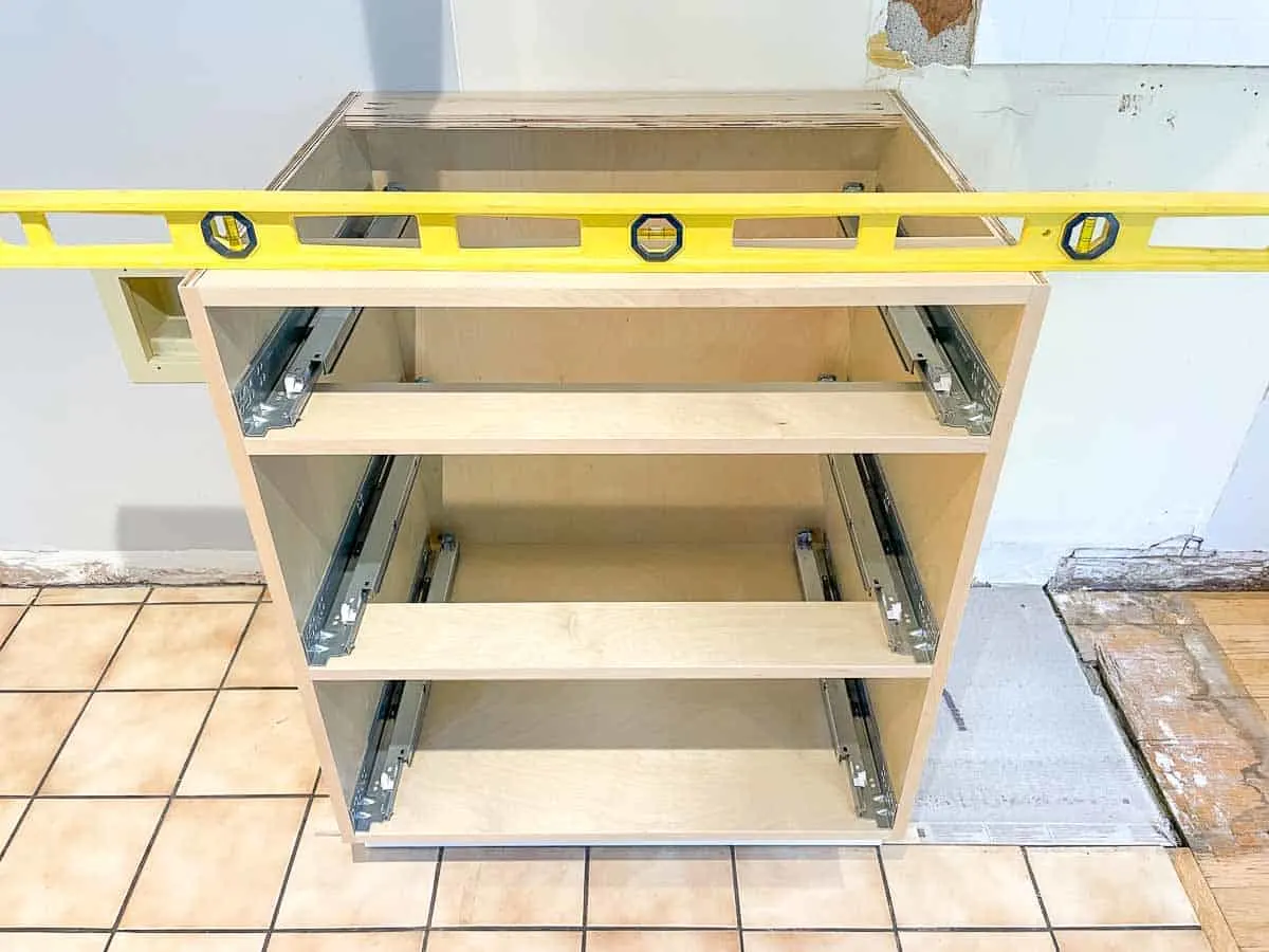 base cabinet with drawers on top of toe kick platform with four foot level on top