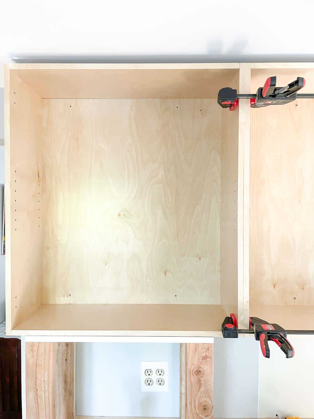 adjacent wall cabinet clamped to middle cabinet while propped up on platform