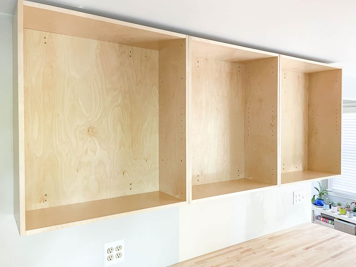 three upper cabinets installed on wall above butcher block countertop