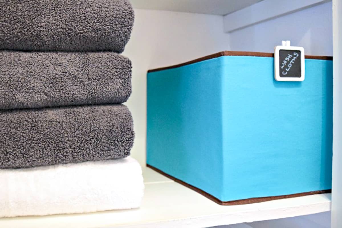 fabric covered box on linen closet shelf with towels
