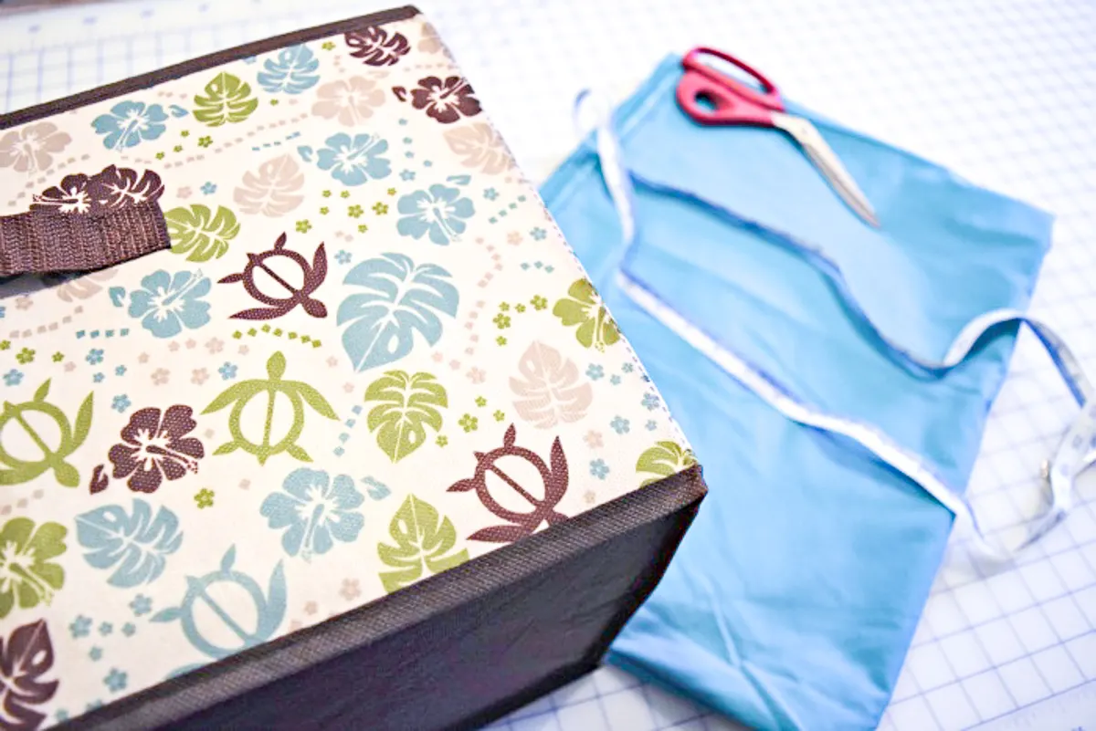 box with fabric, tape measure and scissors in background