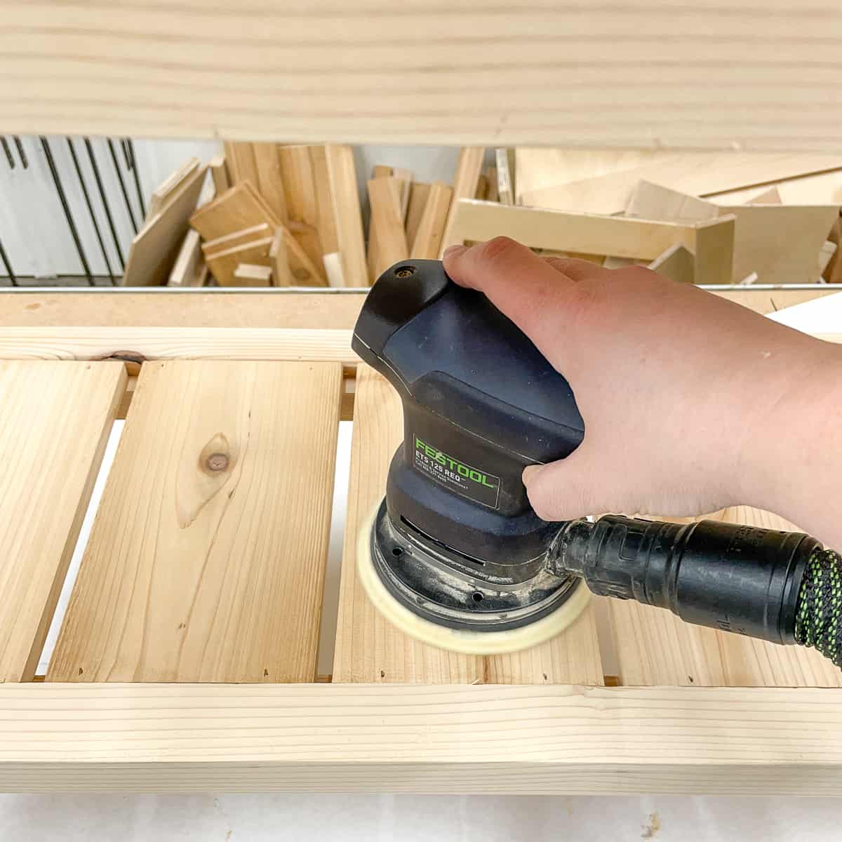 sanding the shelf slats smooth with a random orbit sander