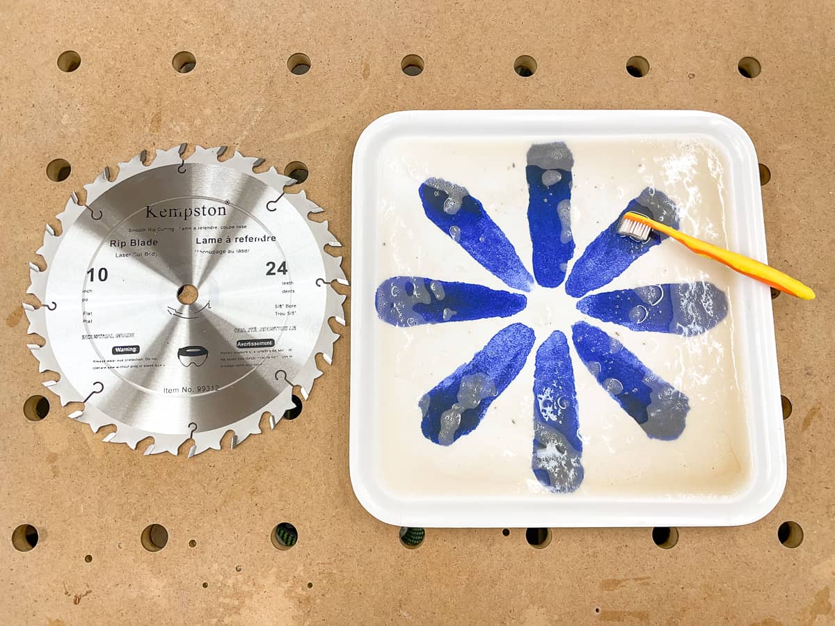 cleaned saw blade with dirty blade cleaning solution in tray