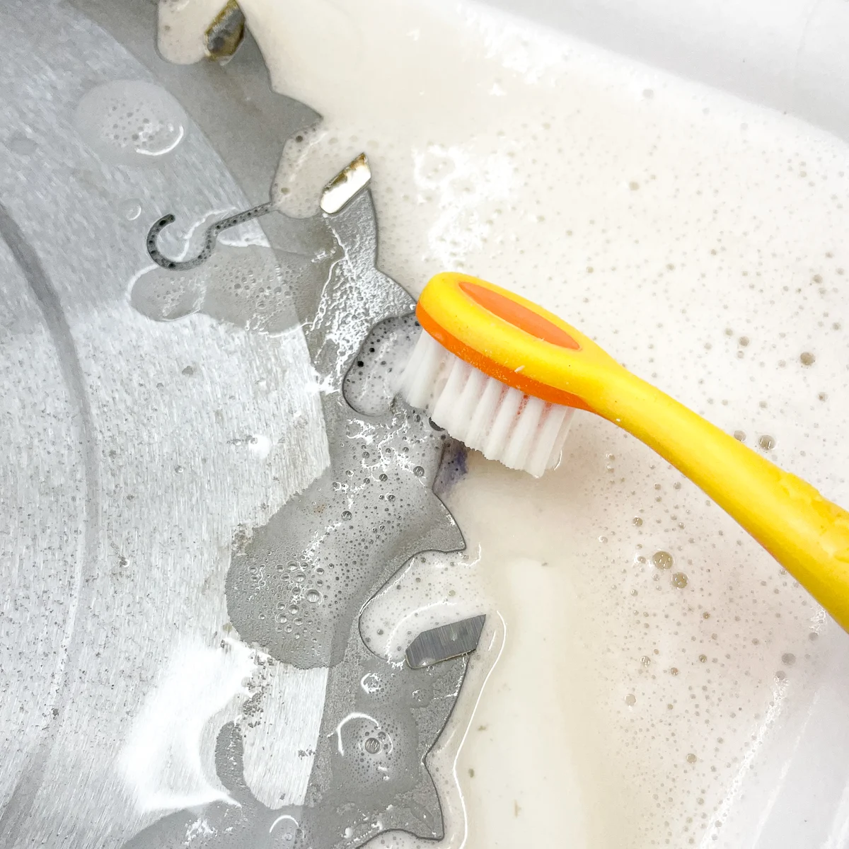 scrubbing the table saw blade teeth with a toothbrush in blade cleaner