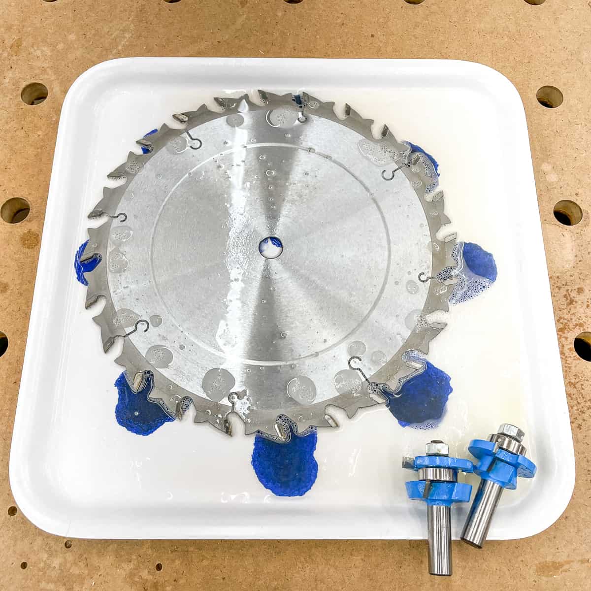 soaking a table saw blade and router bits in a shallow tray with blade cleaner