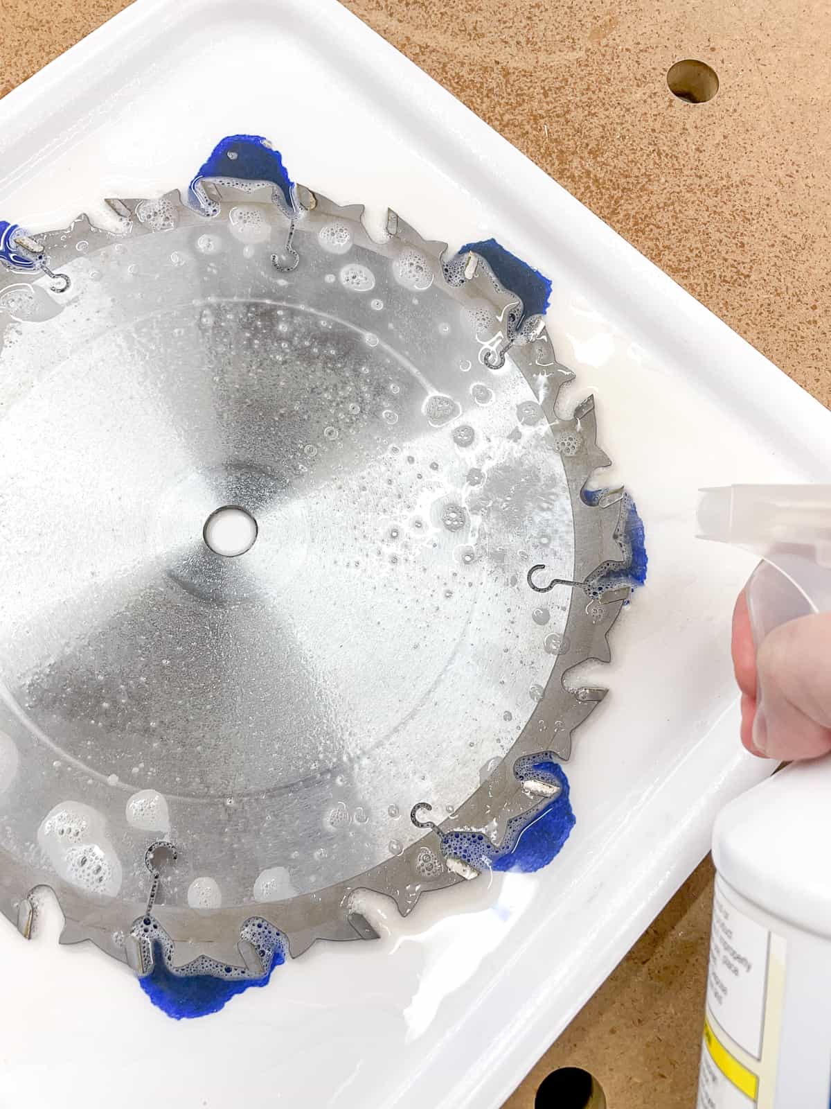 spraying blade cleaner onto saw blade