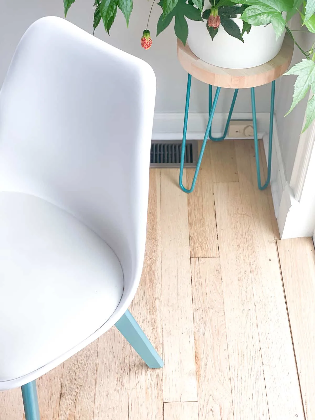 midcentury modern chair with teal legs and plant stand with teal hairpin legs