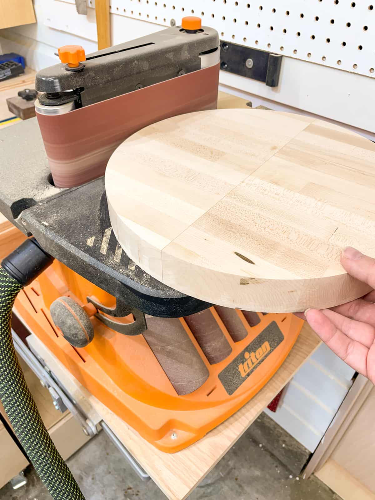 sanding a wooden circle on a benchtop sander