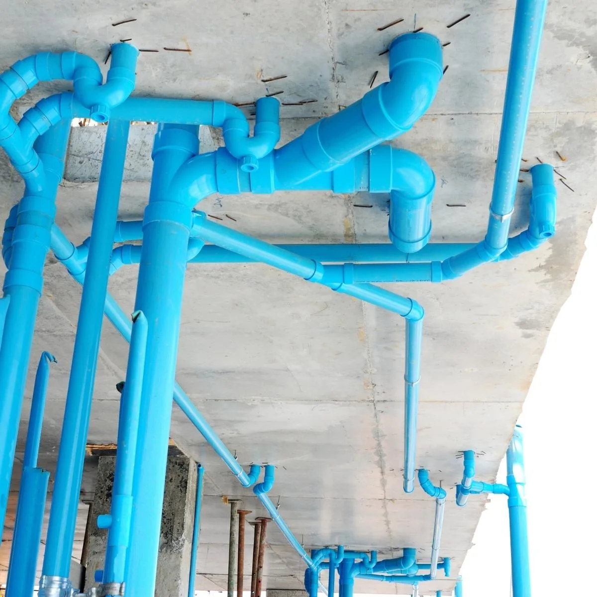 bright blue painted PVC pipe on underside of outdoor concrete structure