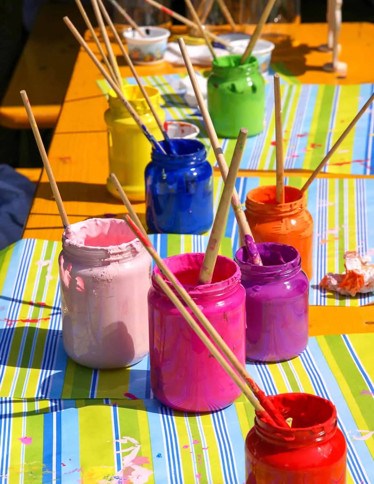 orange table with several different colors of paint in mason jars