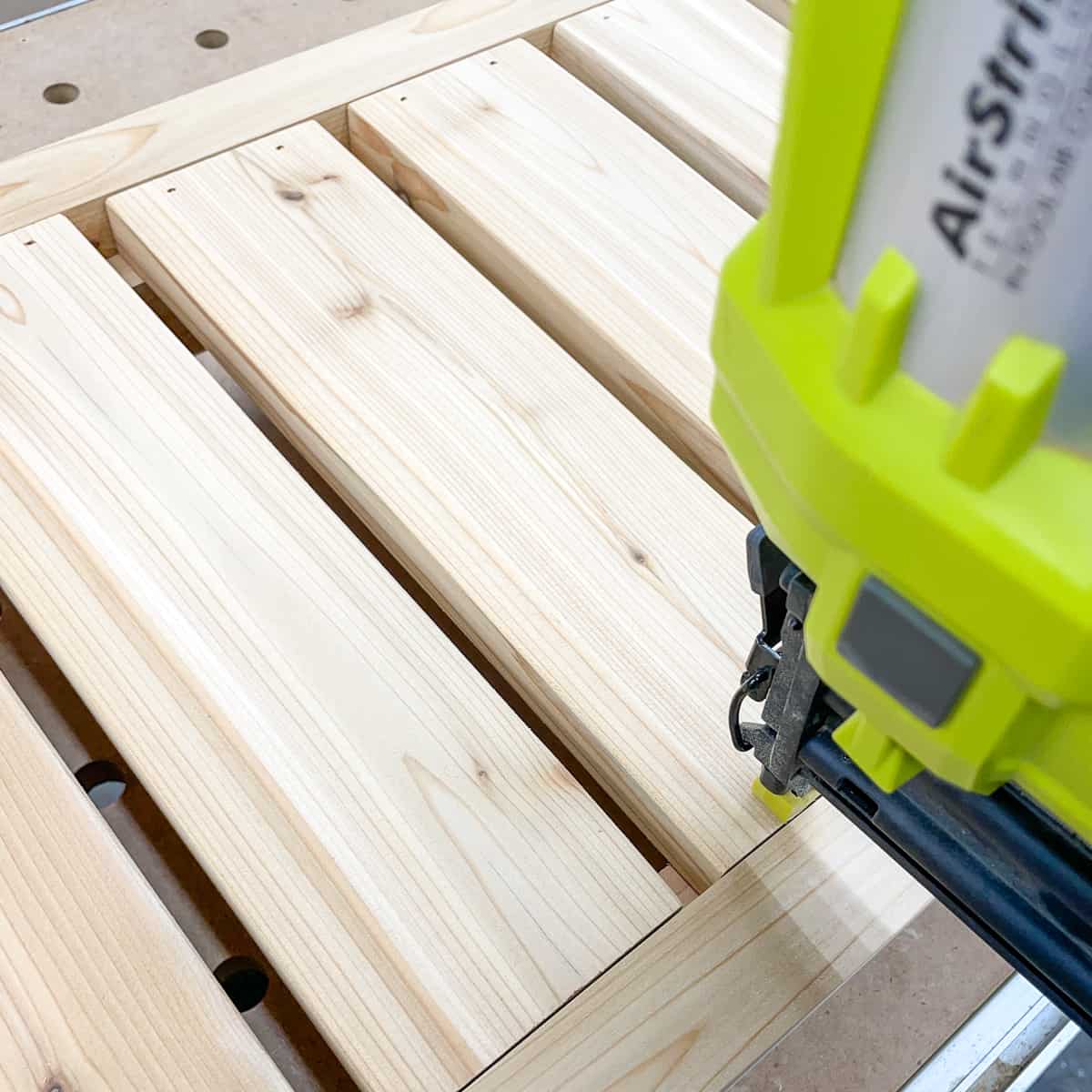 attaching the slats for the bottom shelf of the grill station with a brad nailer