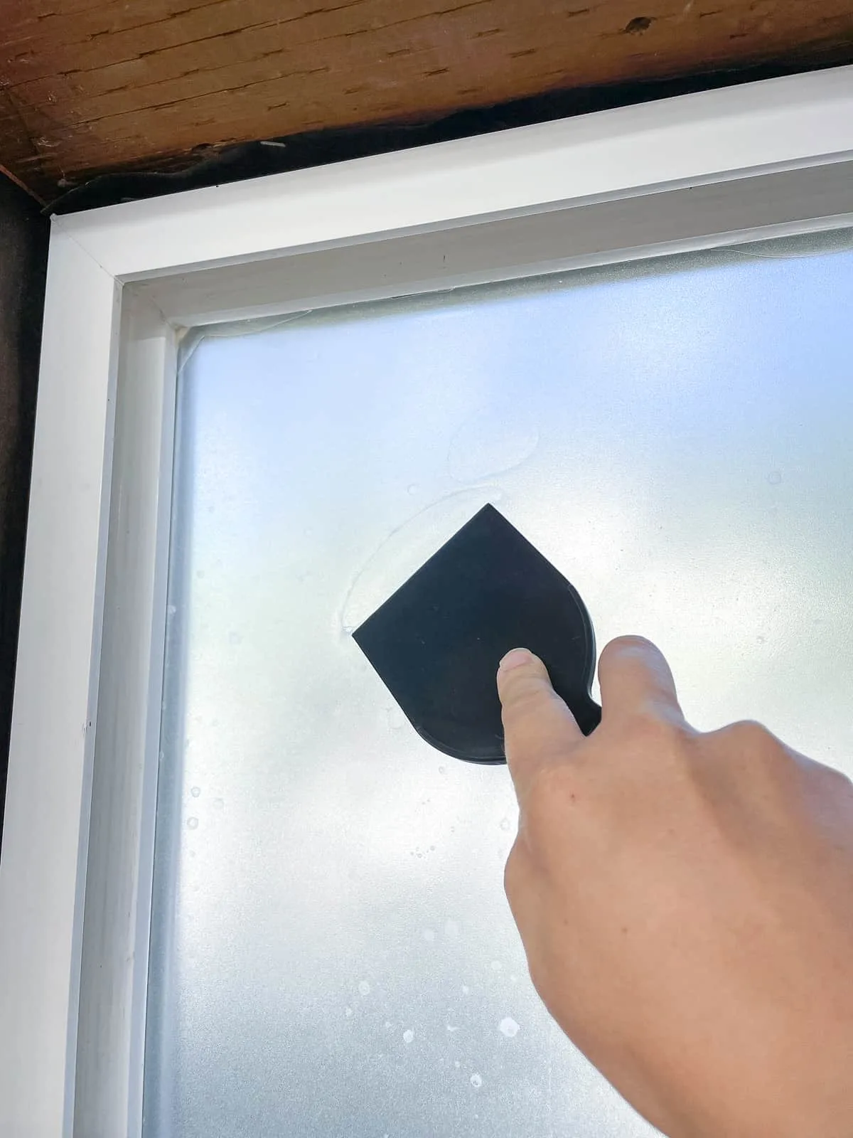 pushing out air bubbles under contact paper on window with a putty knife