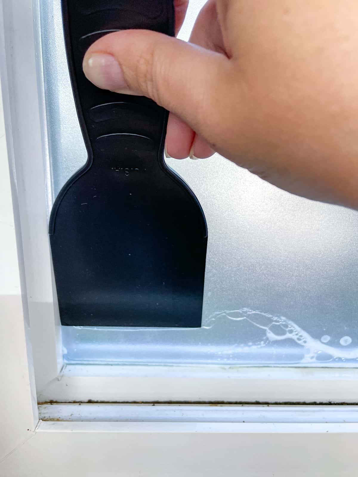 squeezing out air bubbles behind frosted contact paper with a plastic putty knife