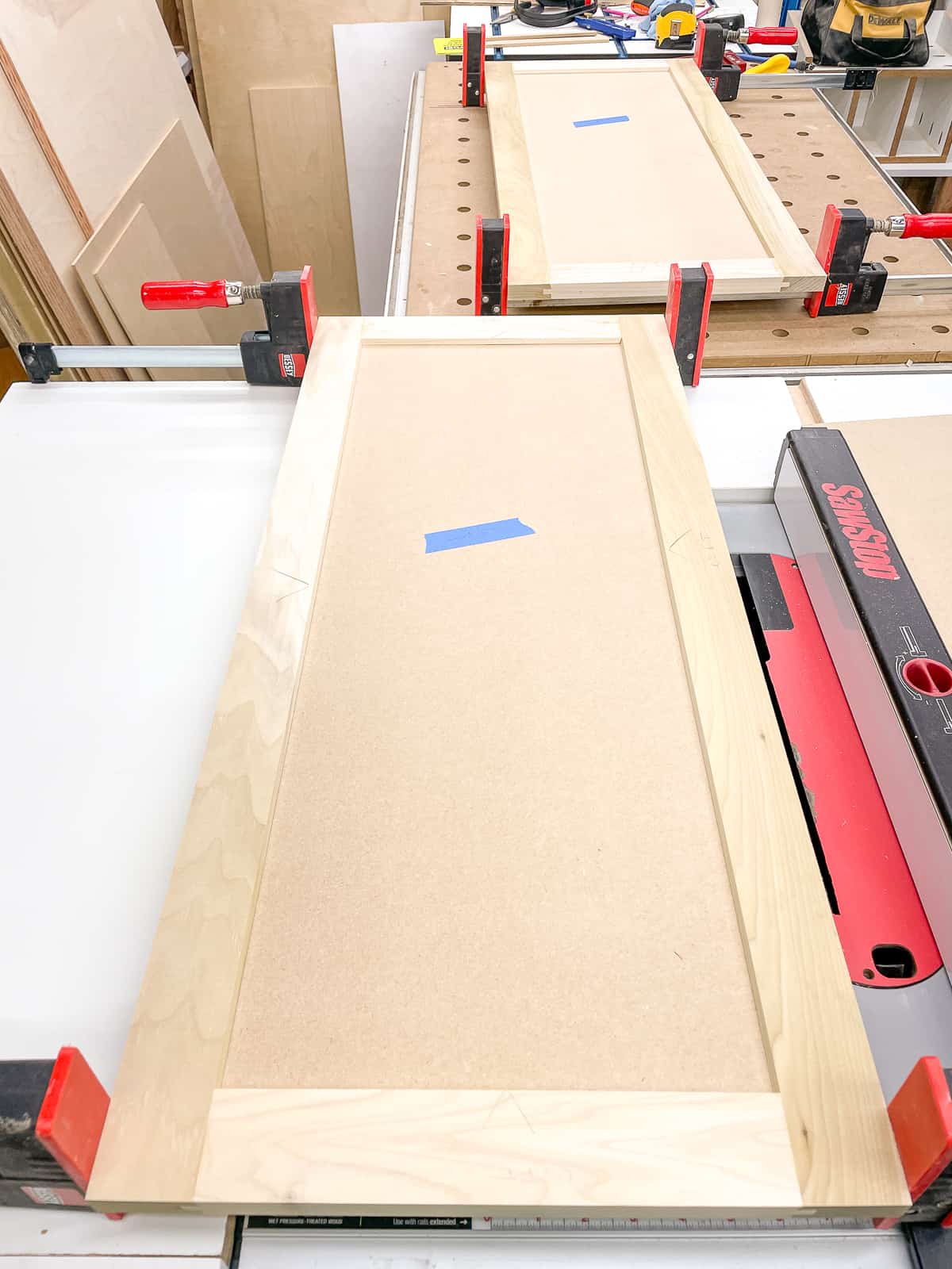 Shaker cabinet doors in clamps on workbench and table saw