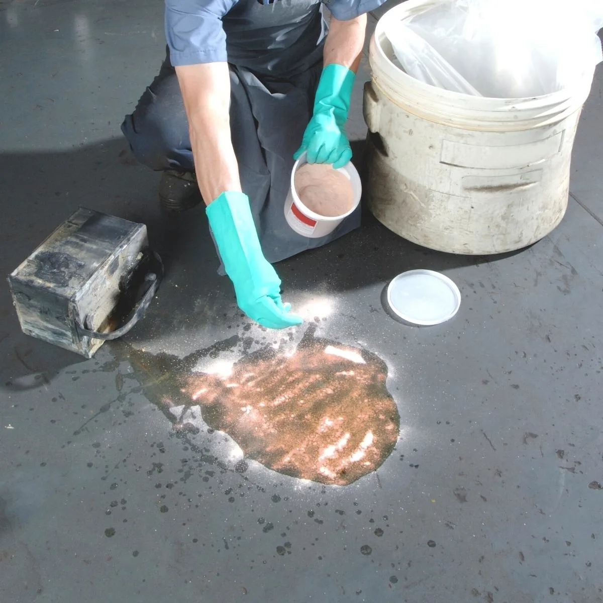 sprinkling sawdust over a spill on a concrete floor