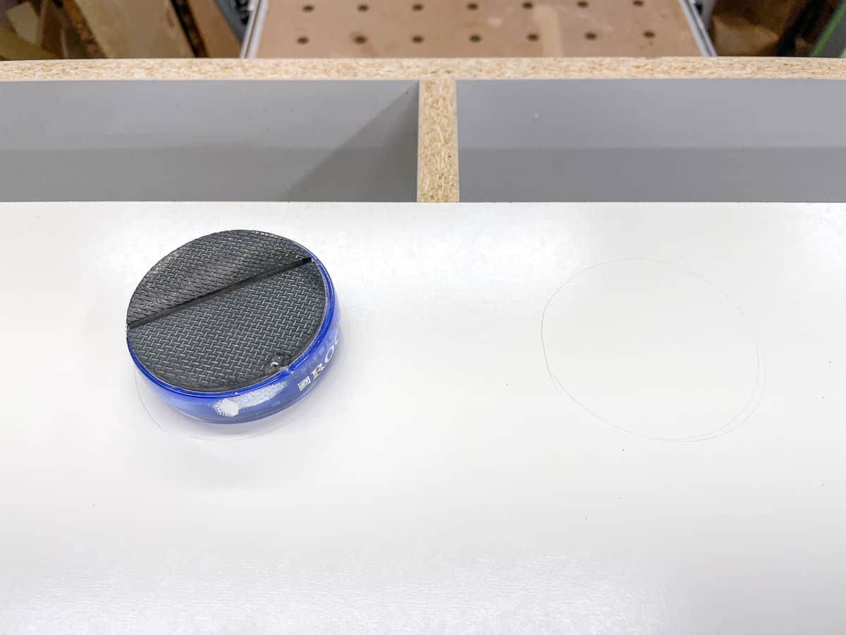 tracing a circular hole on the back of the game console shelf for cords and cables