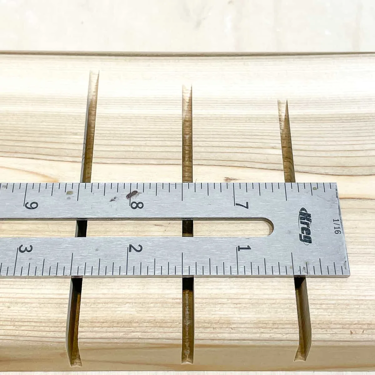 metal ruler on partially cut boards to show how wide the kerf is