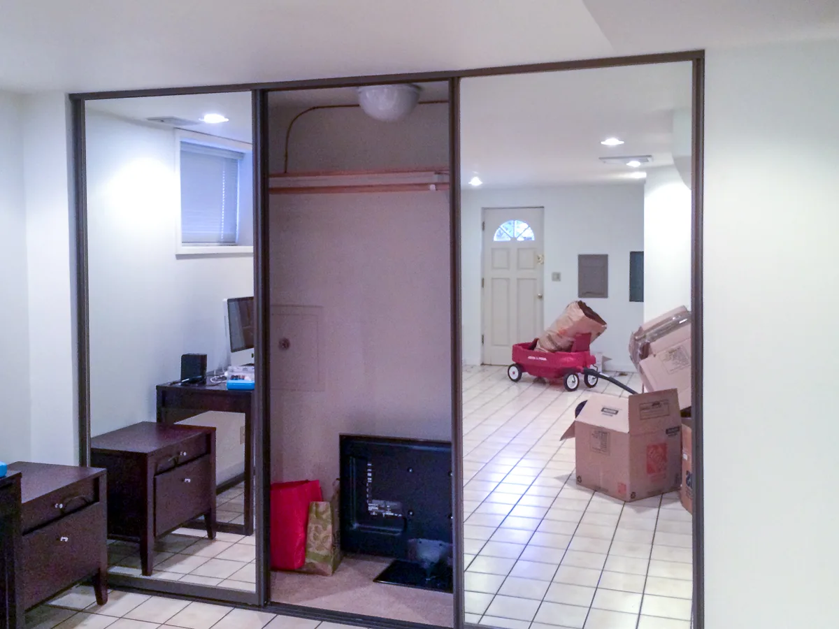 basement family room with large mirrored closet doors on one wall
