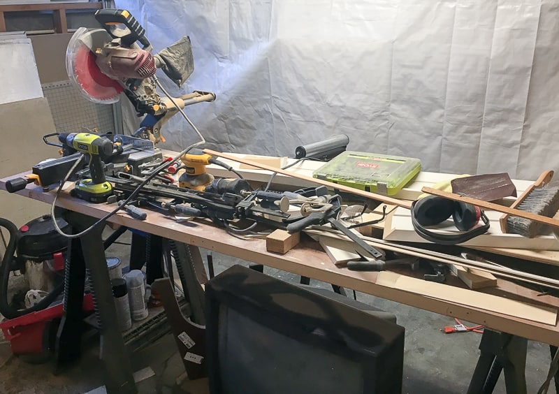 my first workbench with an old door over two sawhorses and tools piled on top