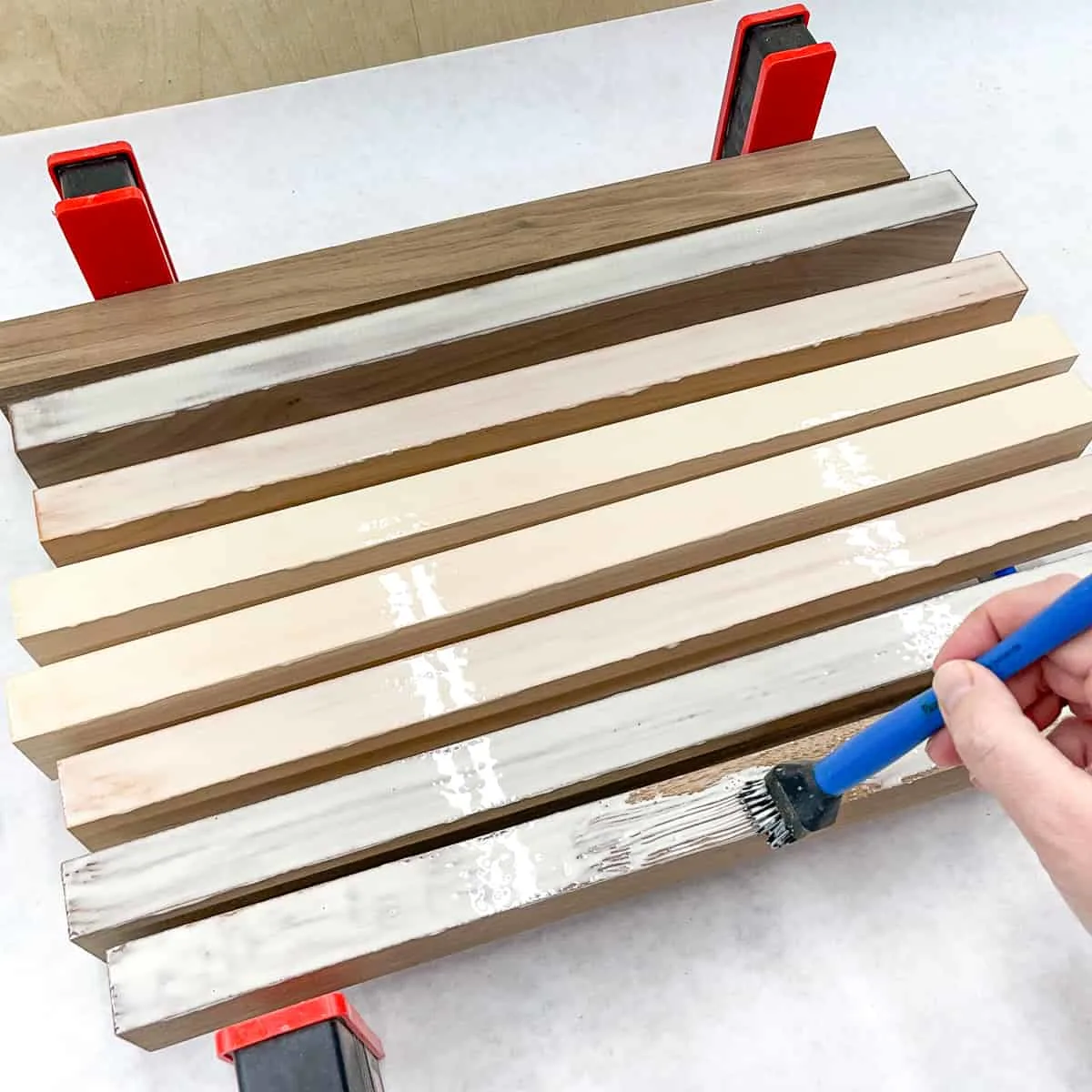 applying wood glue to cutting board strips with a glue brush