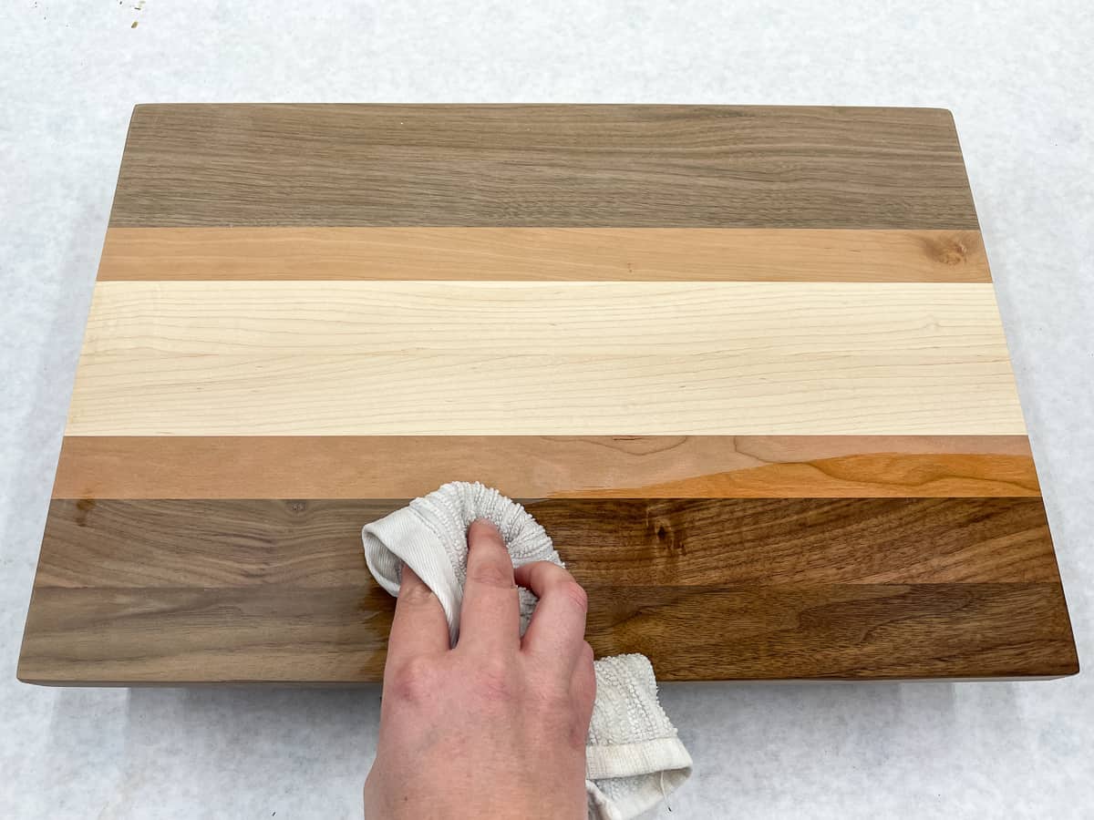 popping the grain of a wooden cutting board with a damp rag