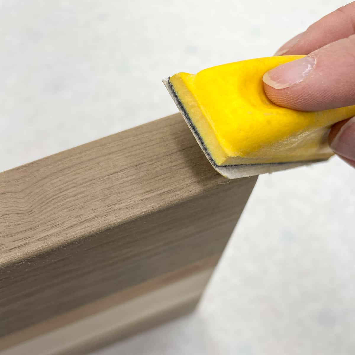 rounding over sharp corners of cutting board with a hand sanding block