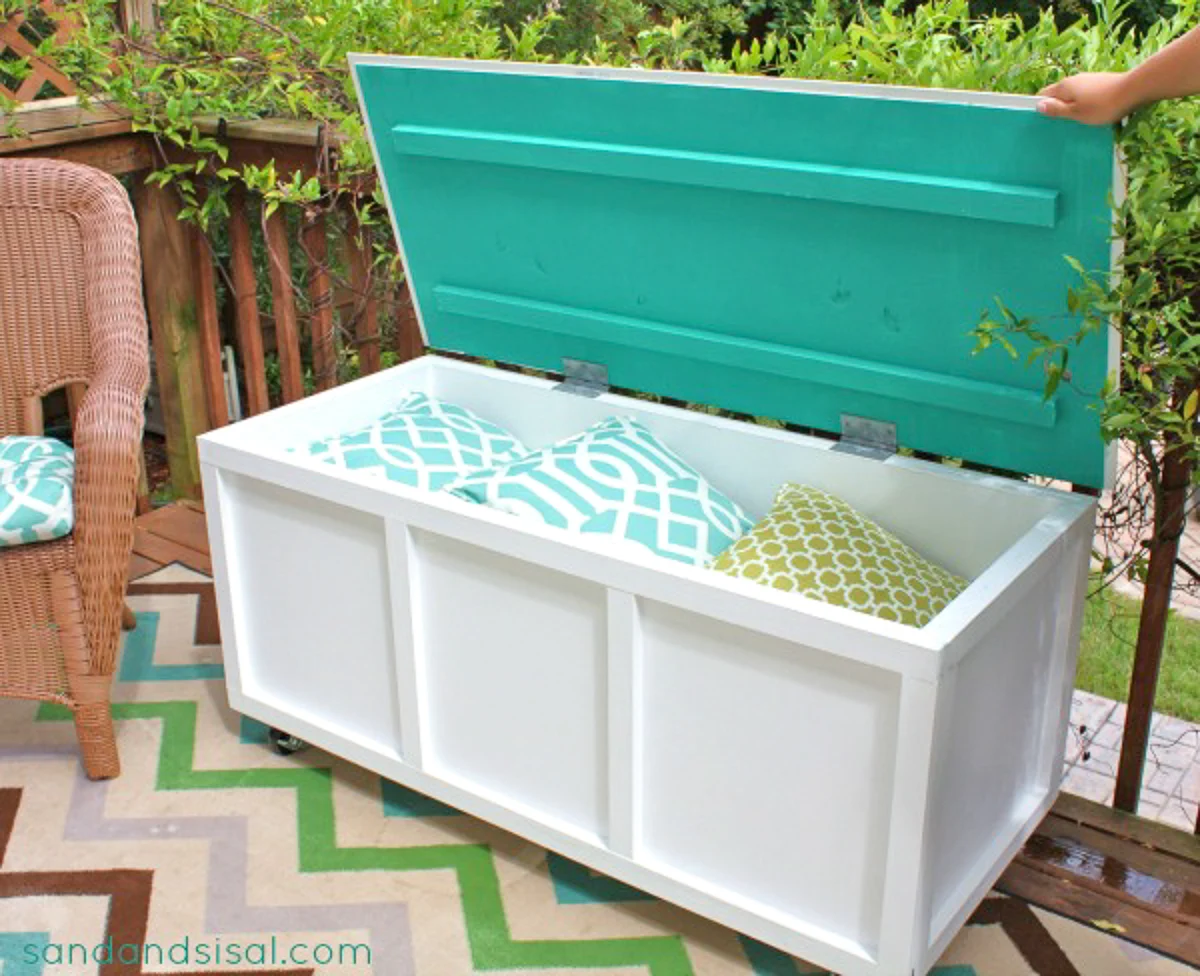 white wooden outdoor storage bench with pillows inside