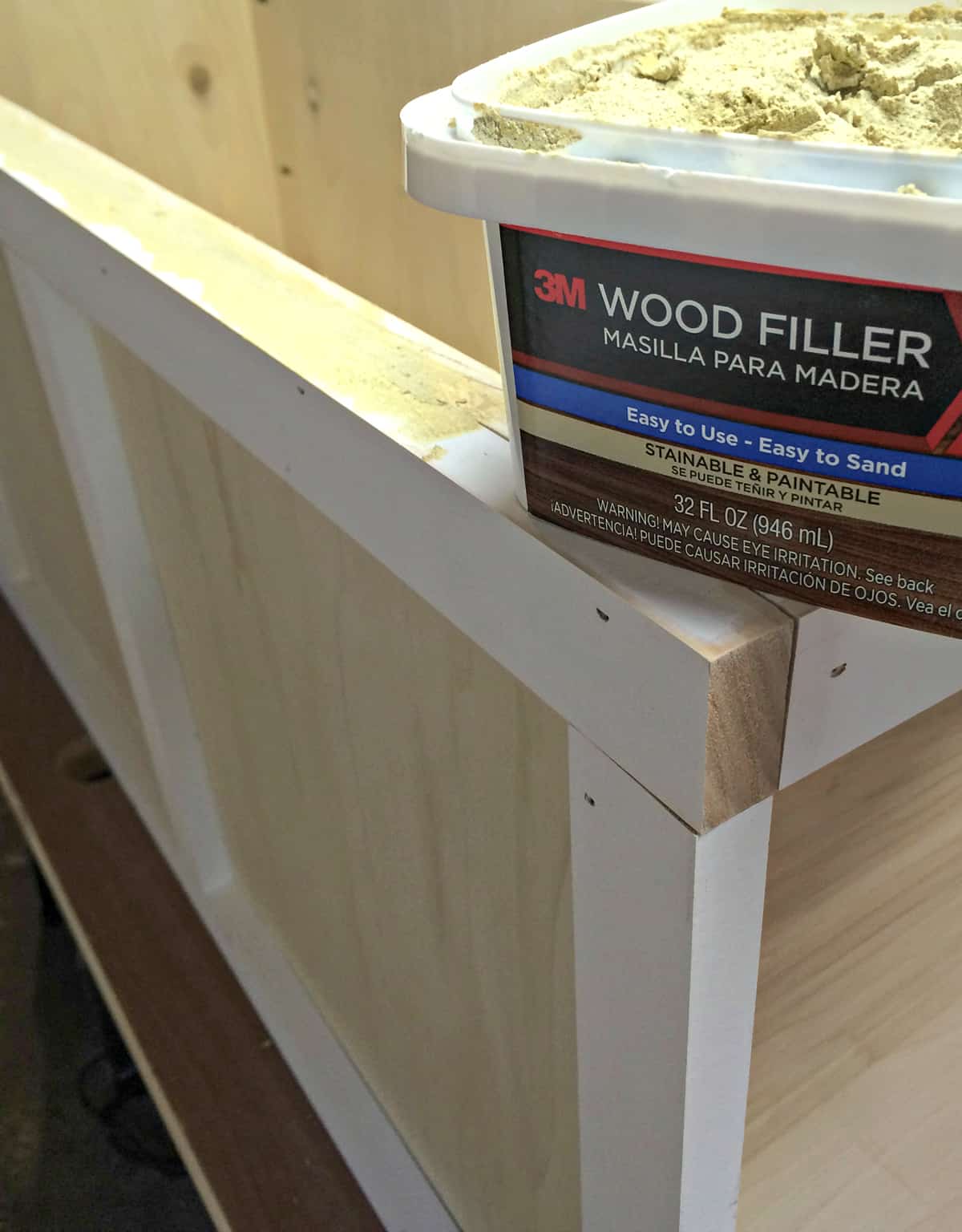 applying wood filler to gaps in storage bench before painting