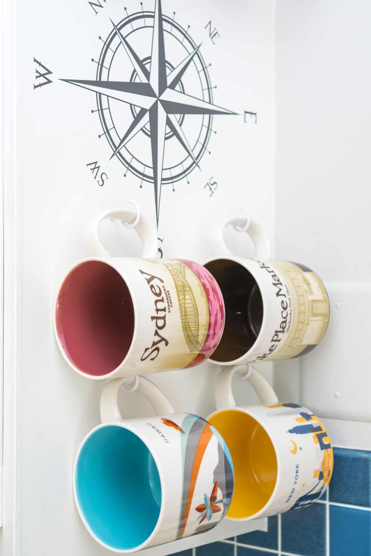 various Starbucks city mugs on display on hooks on side of cabinet