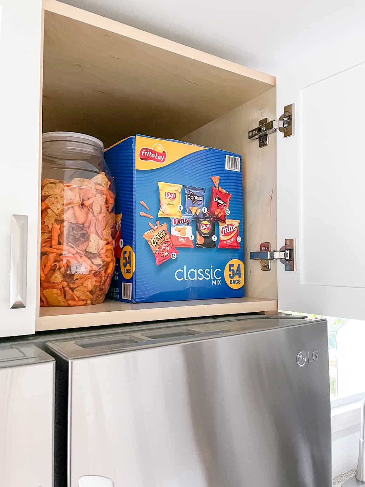 above fridge cabinet open with large box of snacks inside