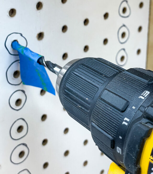 Drill with blue painters tape on tip making holes in board.