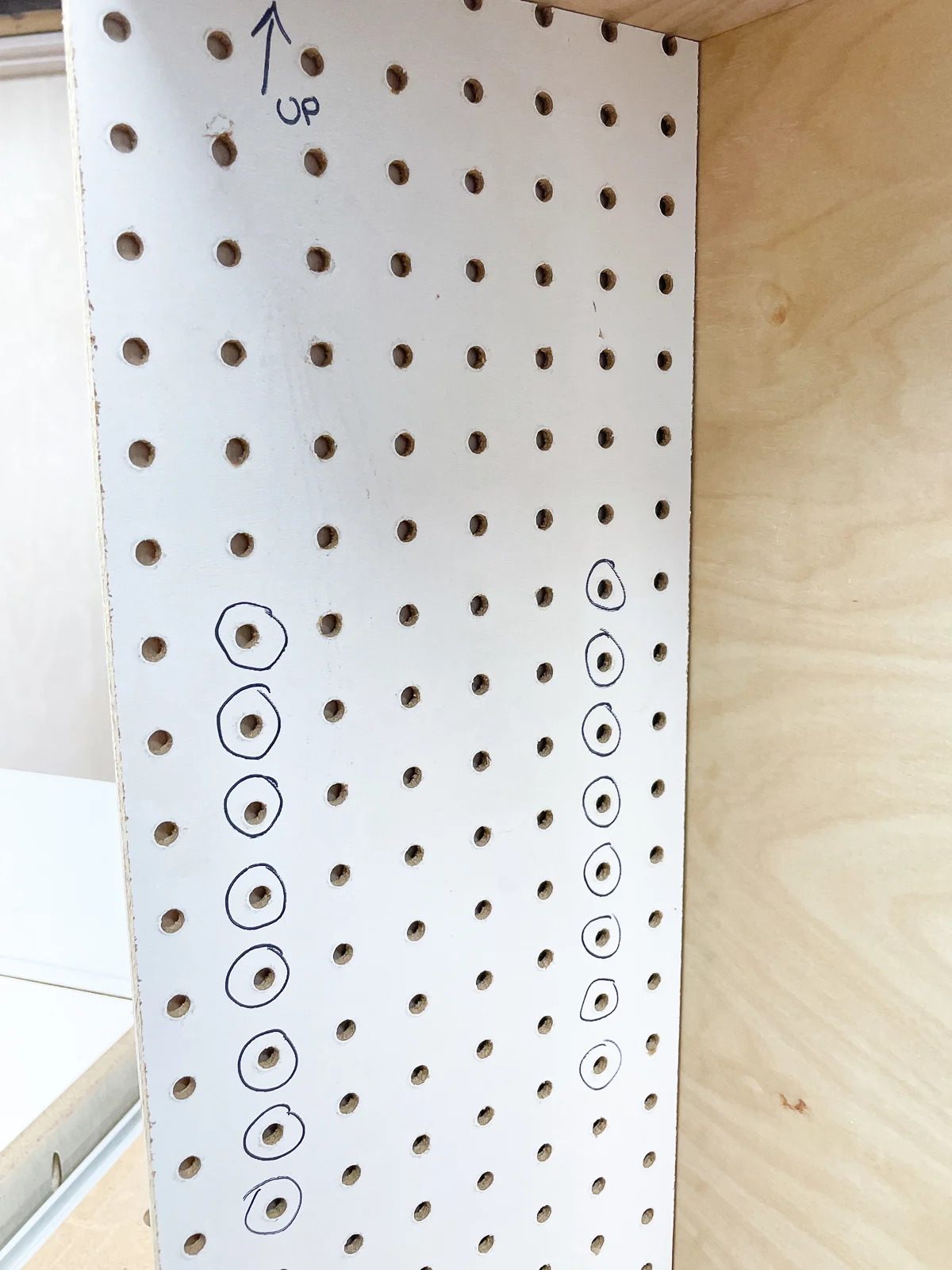 DIY shelf pin hole jig made from pegboard with holes to be drilled circled