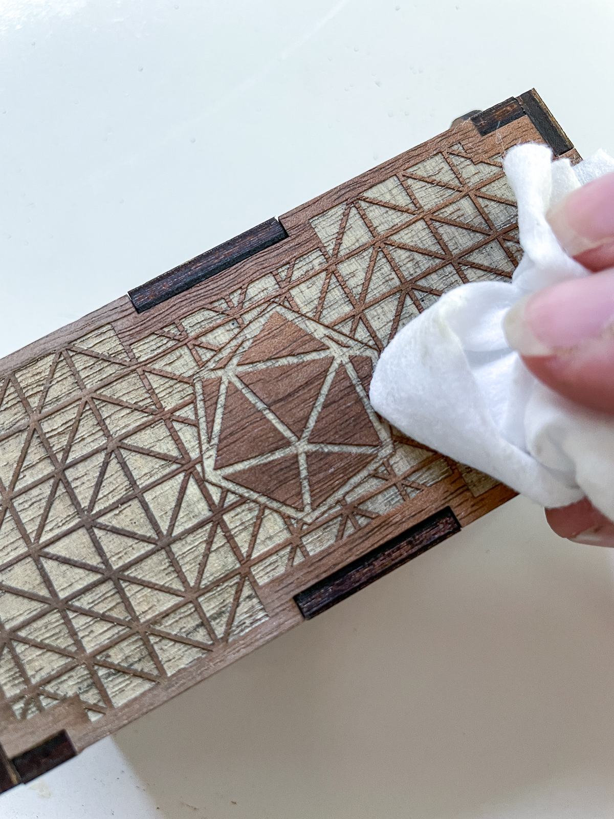 cleaning the surface of the engraved dice box with a baby wipe