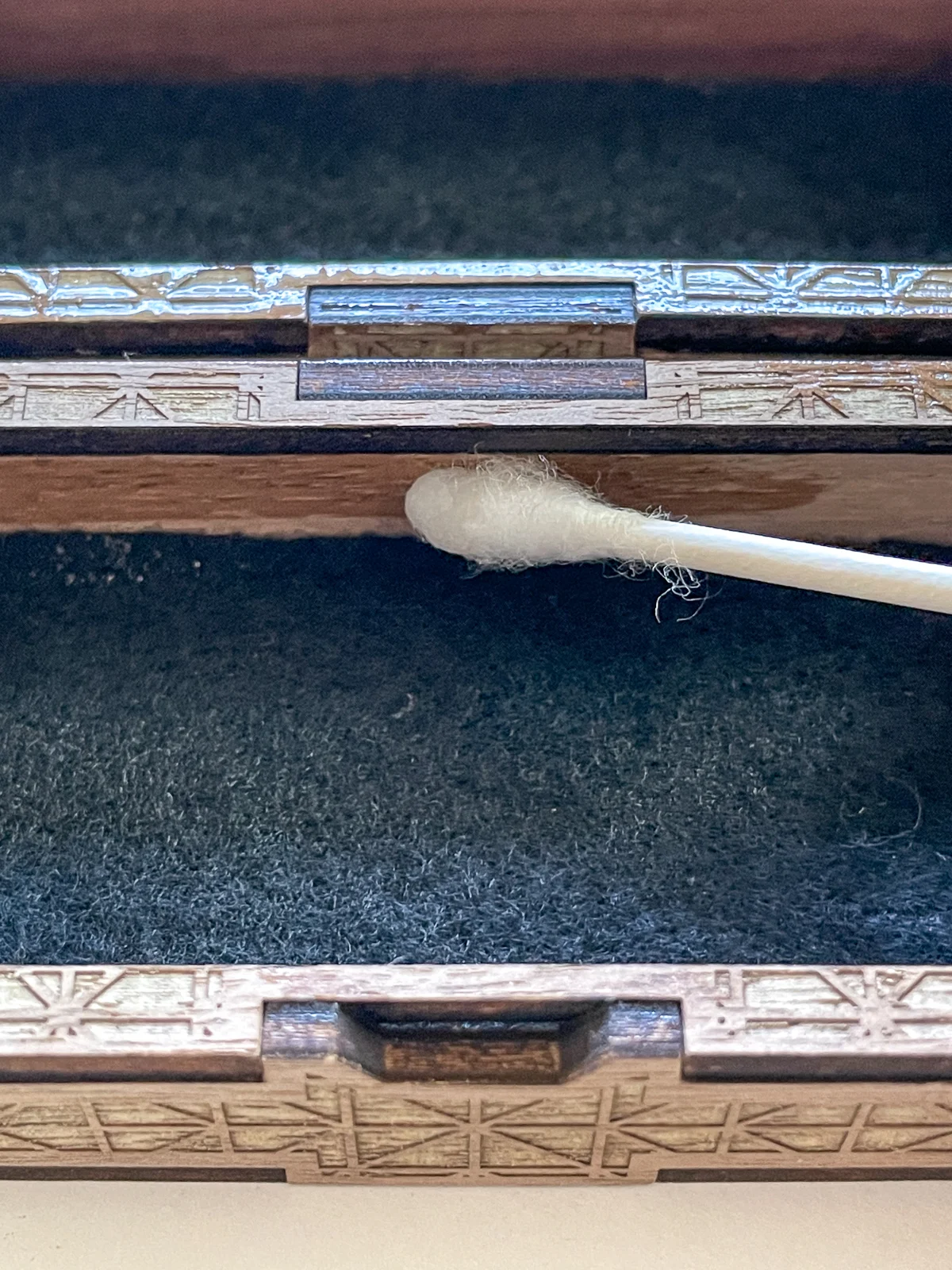 applying oil finish to the inside of the dice box with a cotton swab
