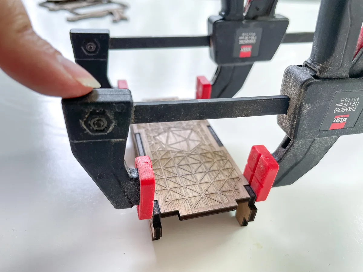 mini clamps holding the DIY dice box parts together while the glue dries