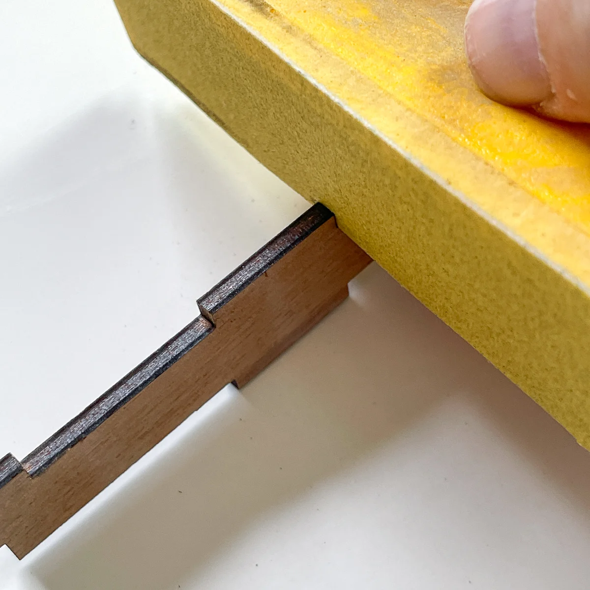 sanding the edges of the notches of the dice box pieces before assembly