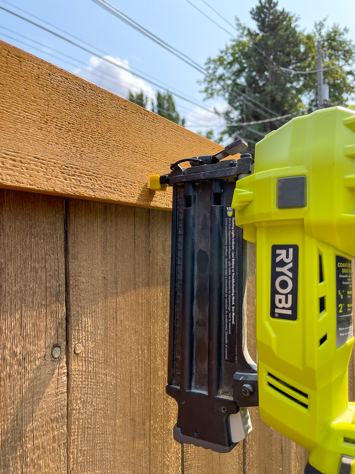 attaching trim to the top of a fence with a cordless brad nailer