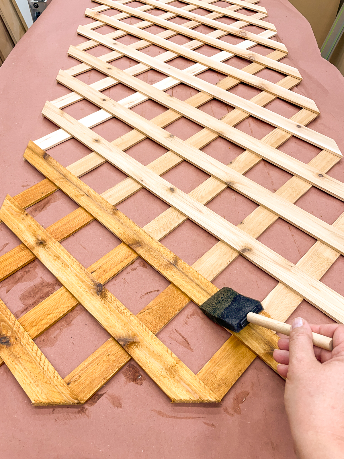 staining lattice for fence top trellis with a foam brush